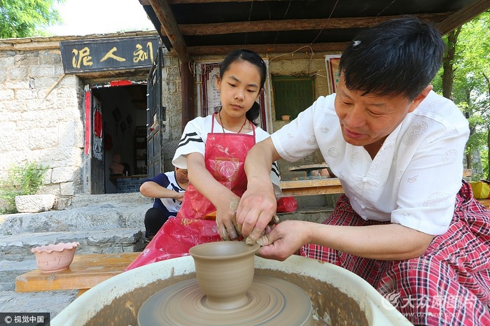 一位小学生在老师的指导下体验传统泥塑制作过程.